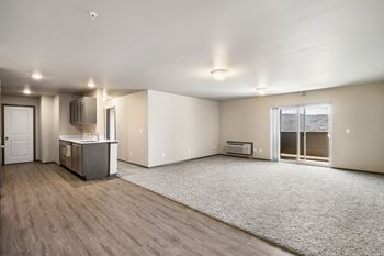 an empty living room with a kitchen and a door to a balcony at Altitude, East Wenatchee, Washington